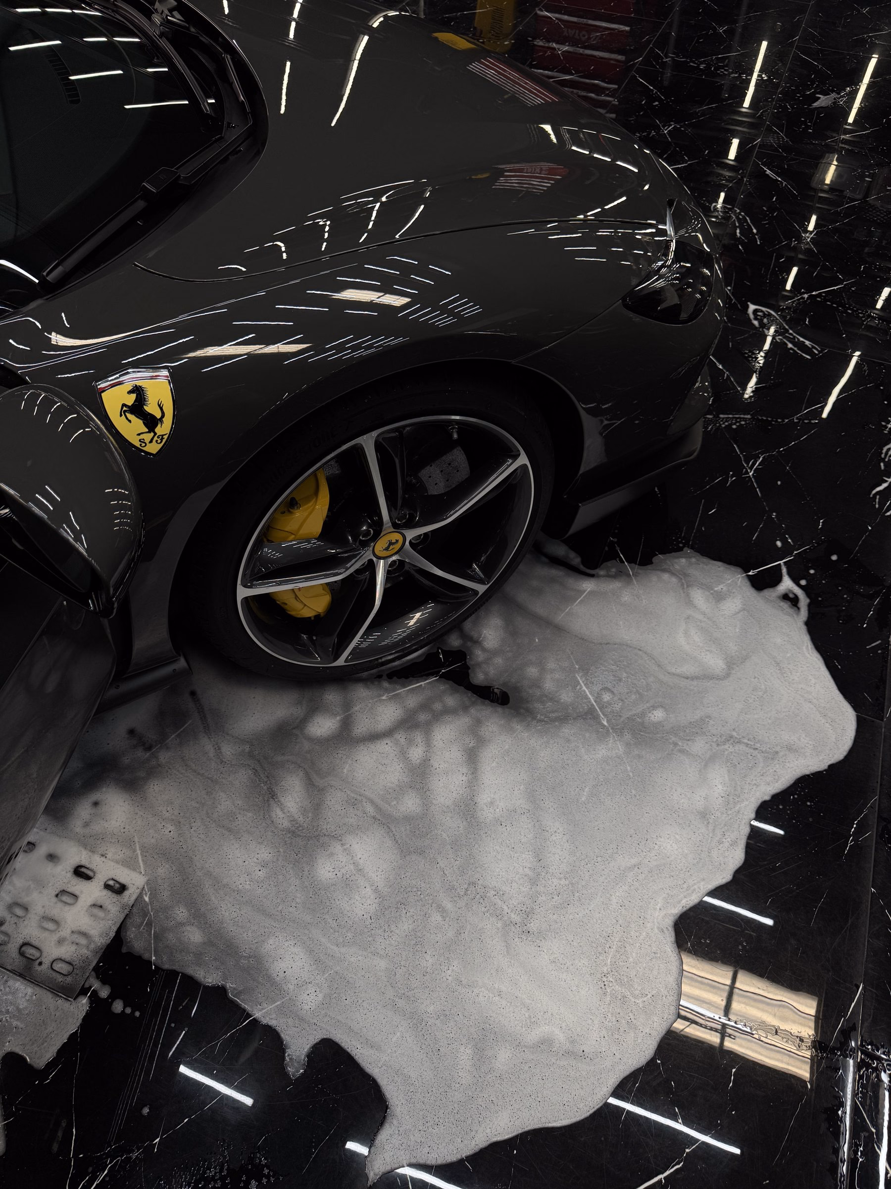Wheel and wheel arch of a Ferrari 812 covered in cleaning foam during a multi-stage hand wash at MAER